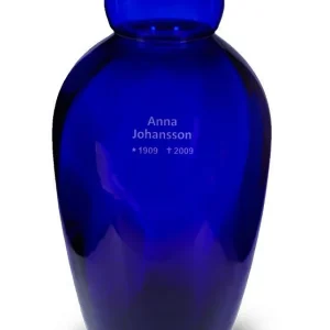 Djupblå glasurna med rundat lock, graverad med namnet "Anna Johansson" samt årtalen "1909 - 2009" på framsidan.